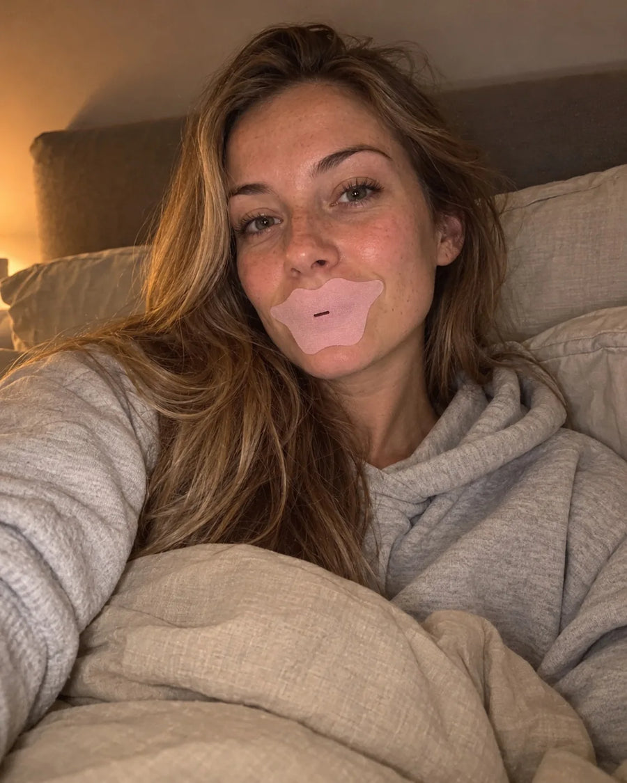 Vrouw in bed met de roze collageen mondtape op