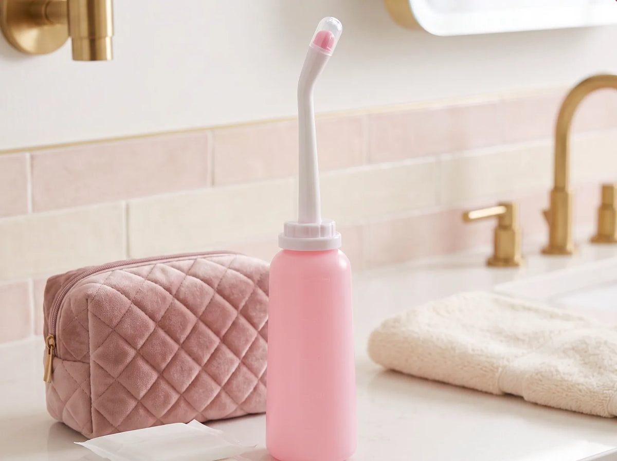 Bidetfles op de wastafel naast een toilettas