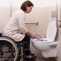 Vrouw in een rolstoel gebruikt de plastuit boven het toilet